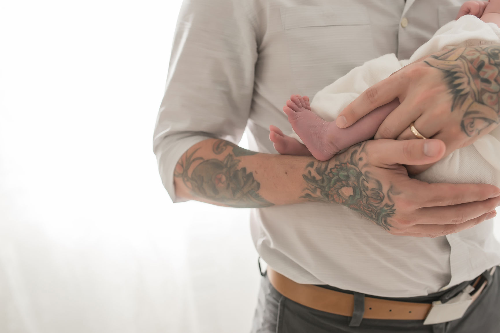 Father's Tattooed Hands Hold Baby