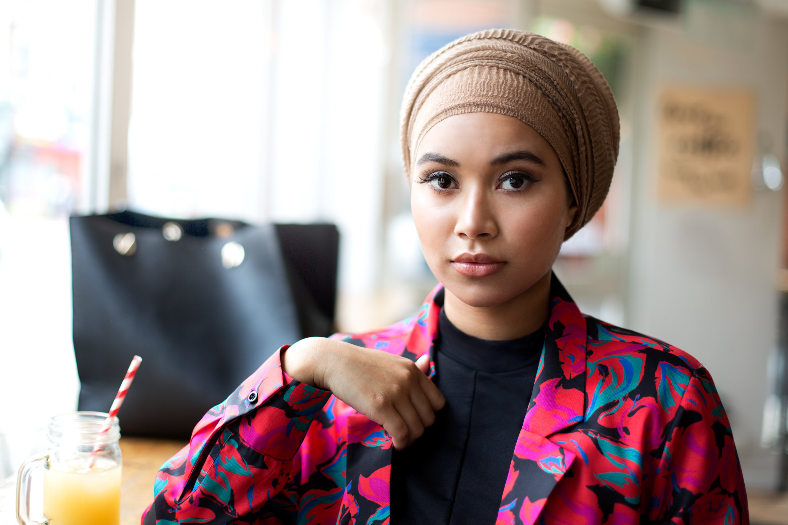 One young muslim woman sitting in cafe looking at camera