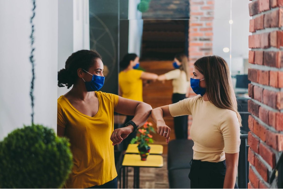 Women in masks elbow bumping