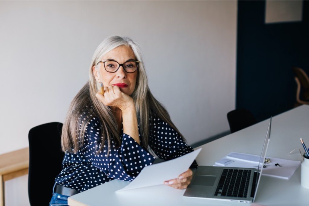 Woman with paper and laptop looking at camera